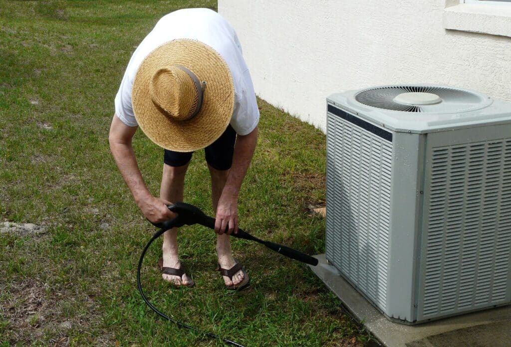 person cleaning off outdoor ac unit