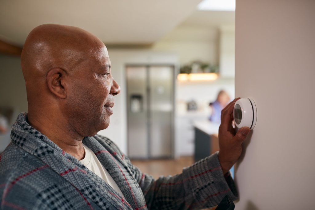 man adjusts thermostat
