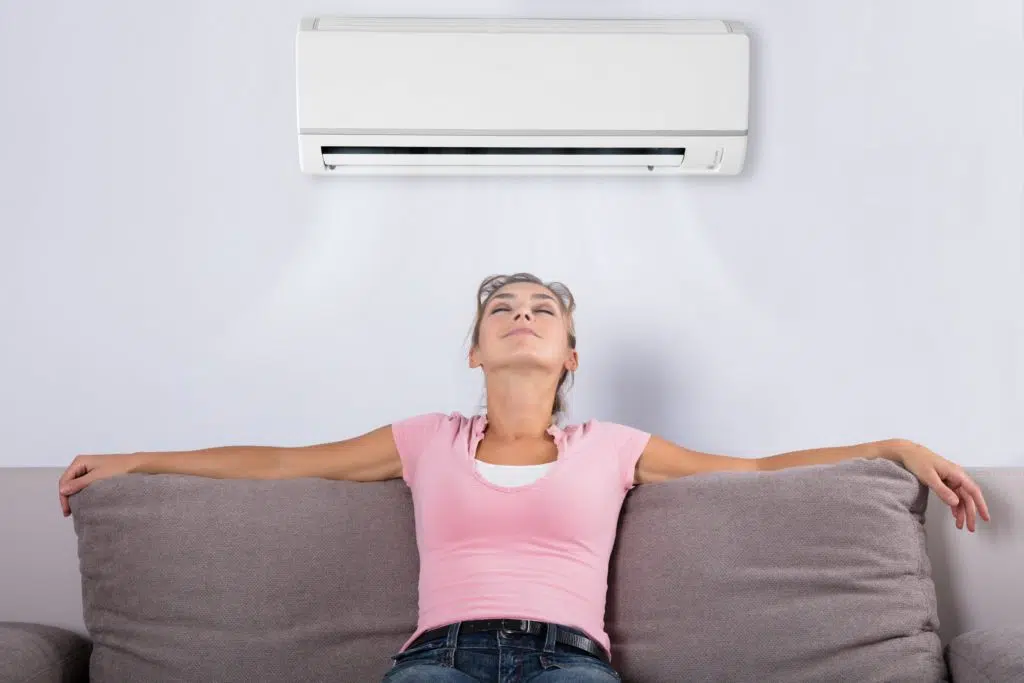 young woman sitting on sofa underneath air conditioner